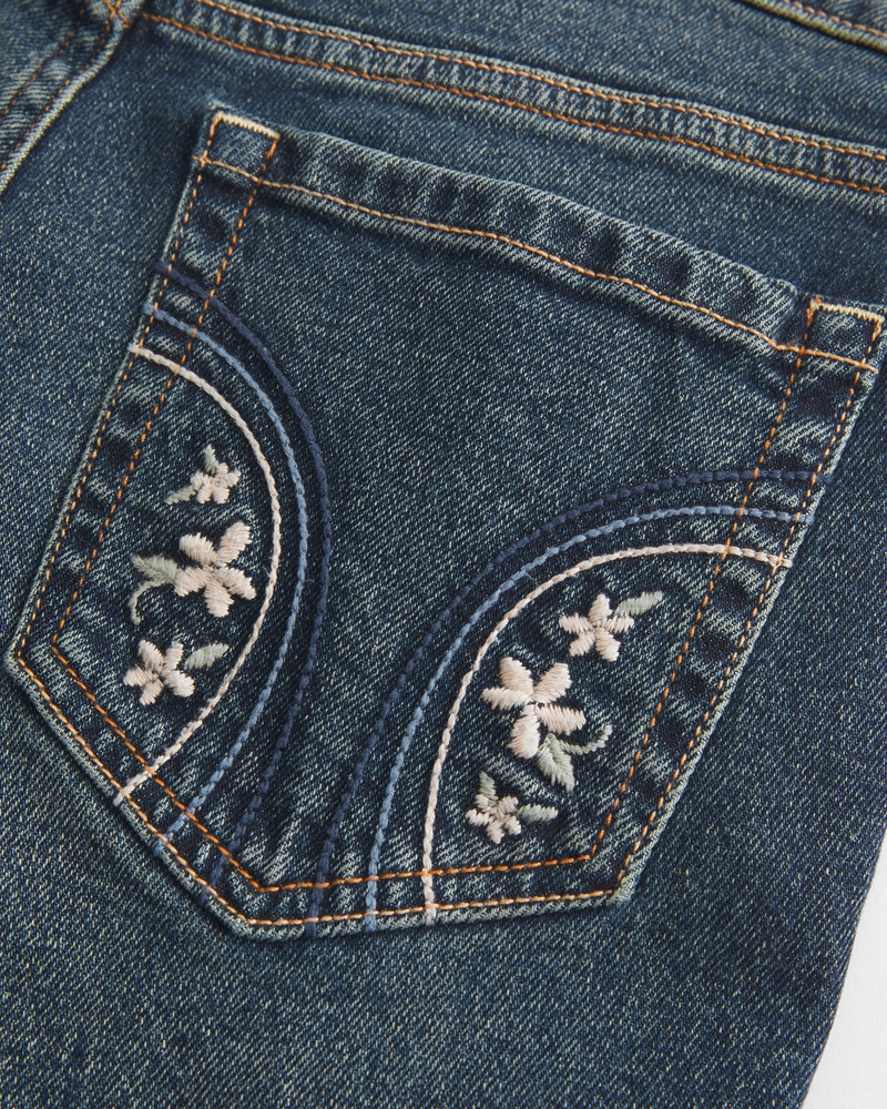 hüftig geschnittene mittelblaue bootcut-jeans mit blumenstickerei.
